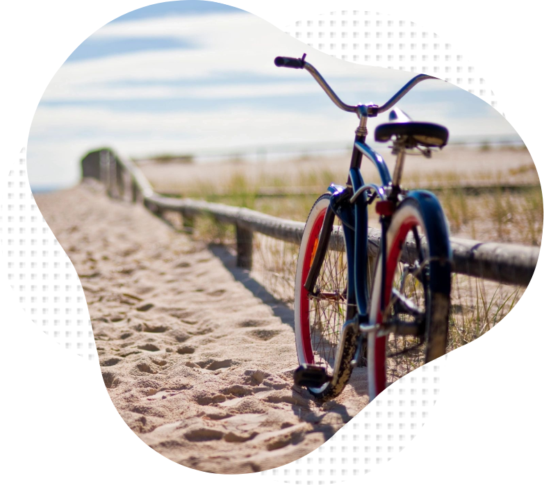 A bicycle parked on the beach near a fence.