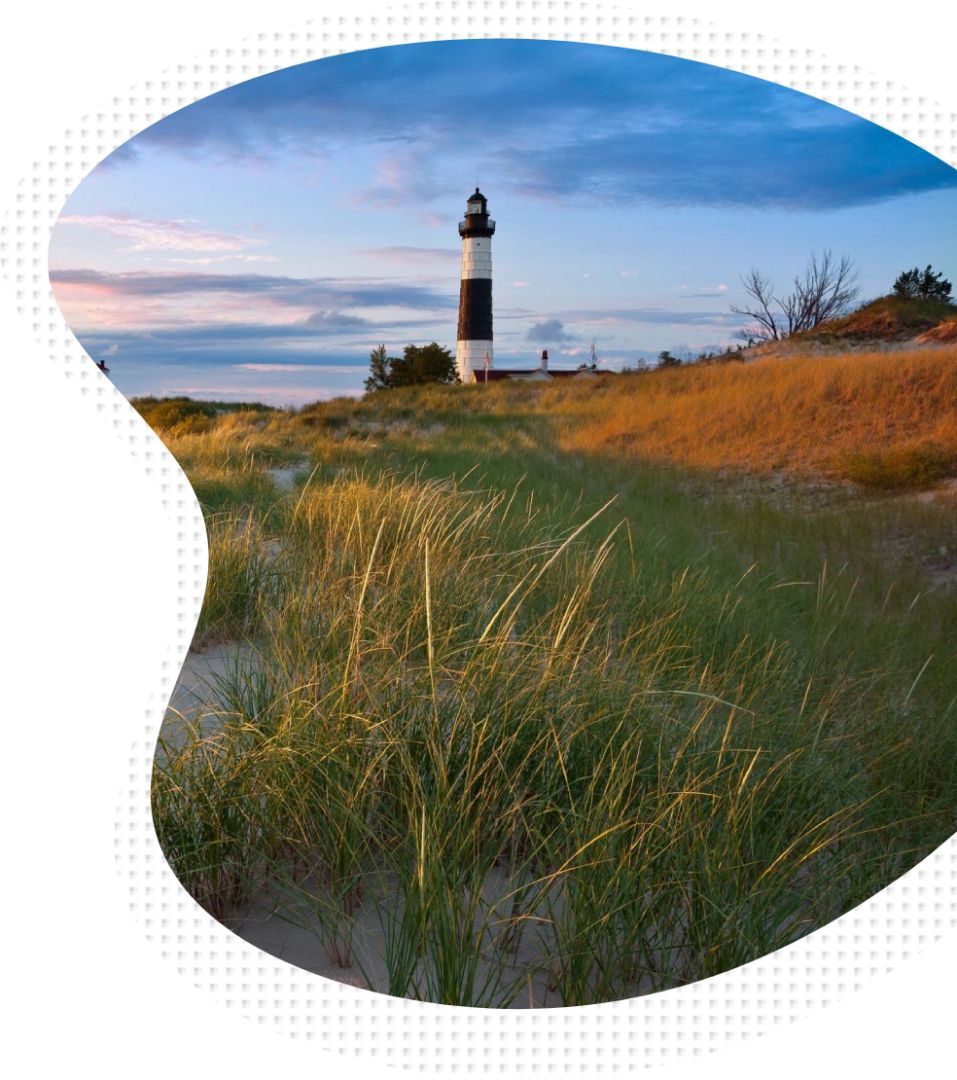 A lighthouse with grass in the foreground and a sky background